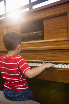 学校教室男孩弹钢琴的后视图