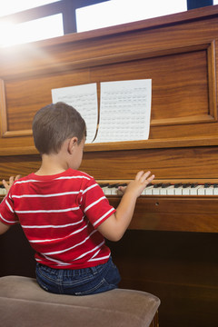 坐在教室里弹钢琴的小男孩