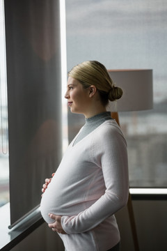 站在办公室窗户旁的怀孕女人