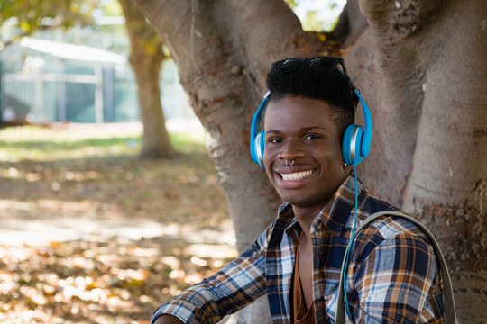 公园里戴耳机听音乐的年轻人