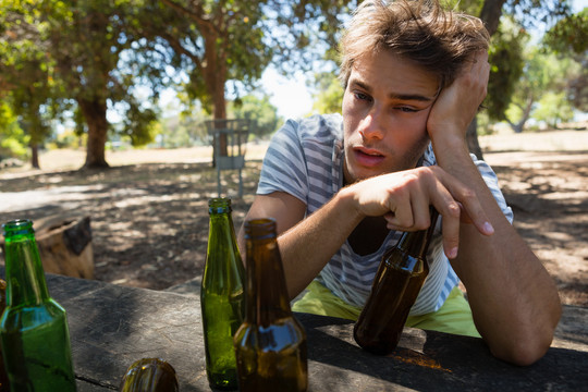 孤独的醉汉在公园里拿着一瓶啤酒