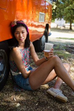 年轻女子在公园里靠着露营车放松