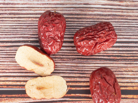 木纹背景上的红枣和切开的红枣