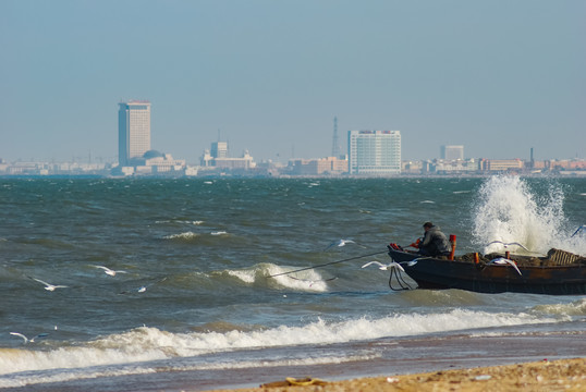 浪花里的渔船海鸥和城市