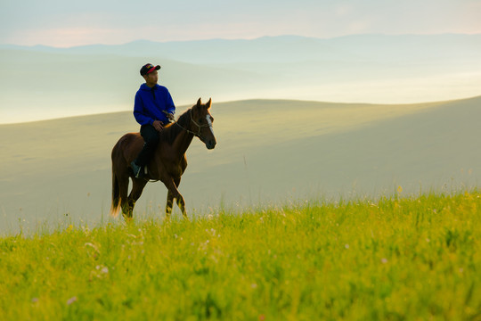 清晨草原骑马的蒙古族男孩
