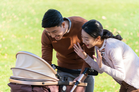 年轻夫妻推着婴儿车散步