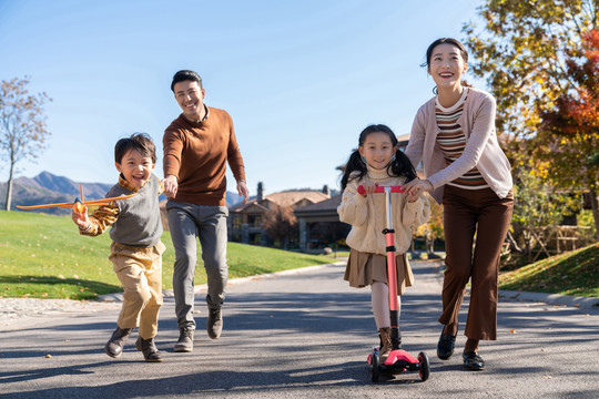 年轻夫妻带着孩子们在玩滑板车