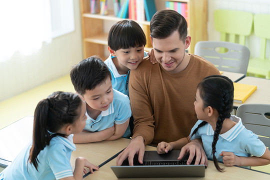 老师在课堂上辅导小学生用电脑