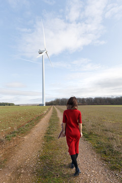 一名女性站在草地上眺望风车
