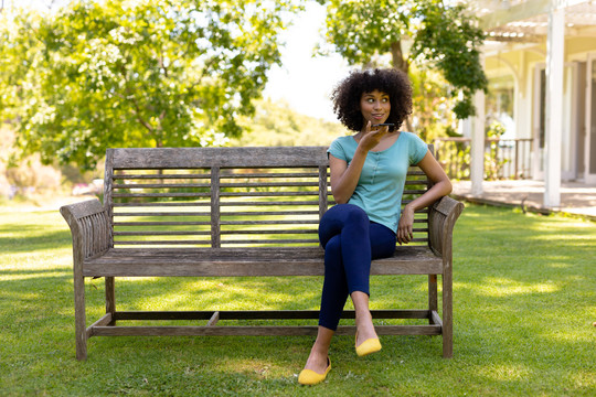 一名混血女子坐在花园的长凳上