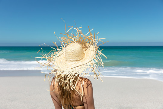 一名戴草帽的妇女站在海滩上