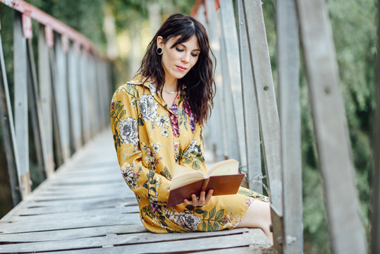 在桥上看书的年轻女子
