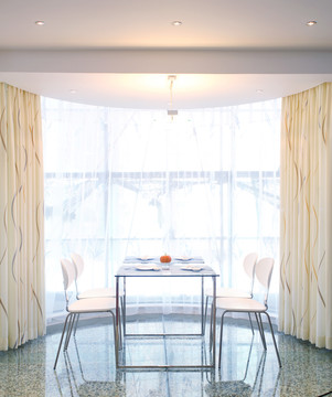 窗前的白色椅子与玻璃餐桌