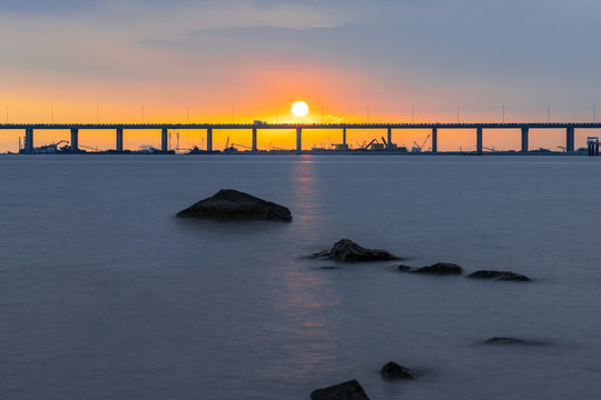 黄昏落日下的跨海大桥和礁石