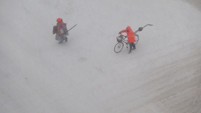 俯拍大雪中行走的环卫工人