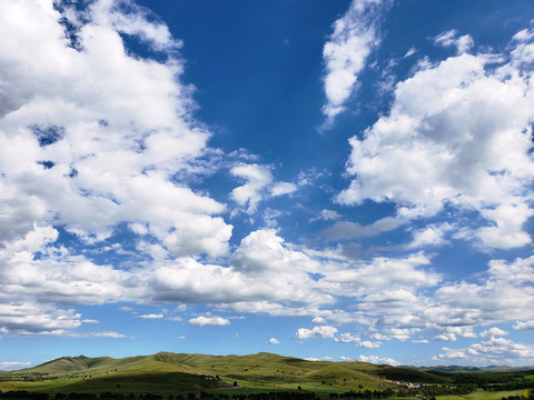 蓝天白云下的山丘和草原村落