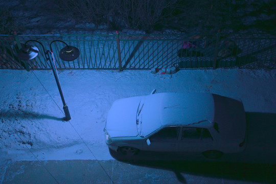 极寒夜晚街灯下覆盖积雪的轿车