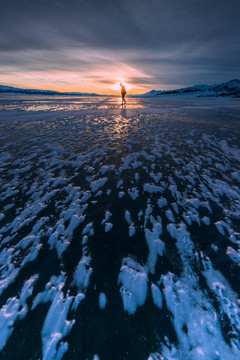 游客在冰雪赛里木湖的日落