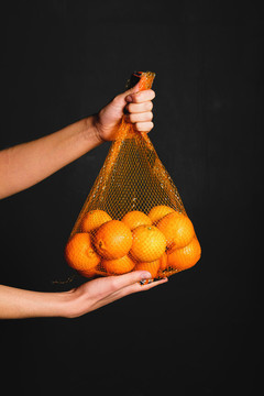 手拿橙子在网袋里