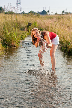女人站在一条小溪里，脚踝浸在水里，凉水在夏日的炎热中沁人心脾
