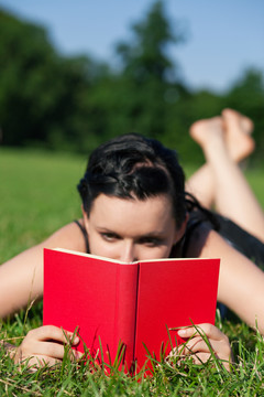 女人在阳光下看书，夏天躺在草地上，专注的是书