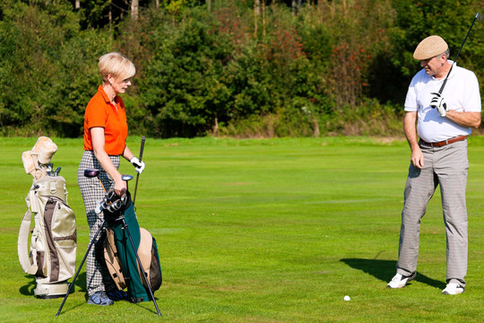 成年或老年夫妇打高尔夫球，走在球场上