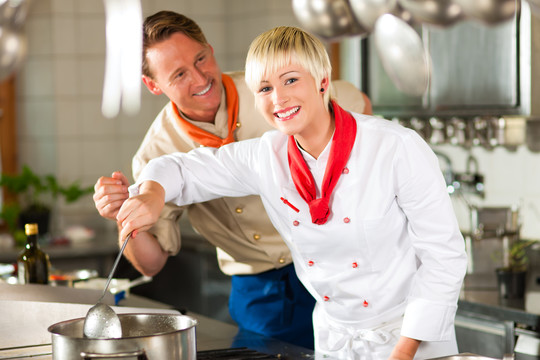 两个厨师团队合作-男人和女人-在餐厅或酒店厨房烹饪美味的食物