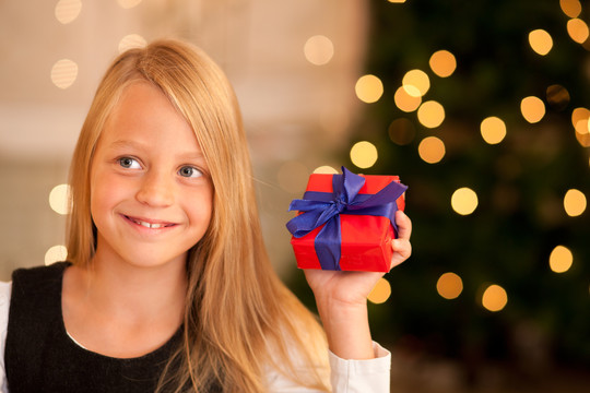 在圣诞树前拿着礼物的女孩