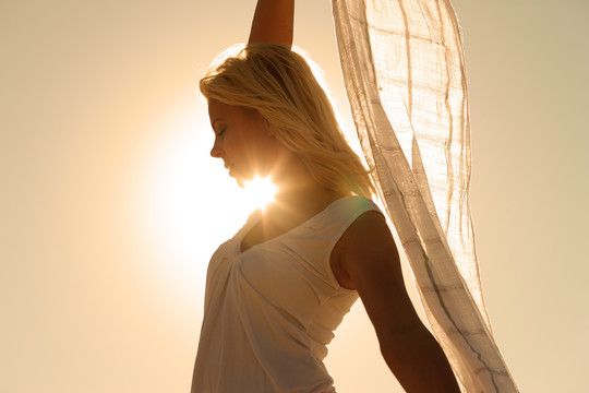 戴着白领巾的女人站在风中，在阳光的照耀下感到幸福和平衡