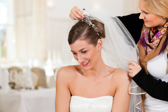 发型师在婚礼前给新娘扎上发型和新娘面纱