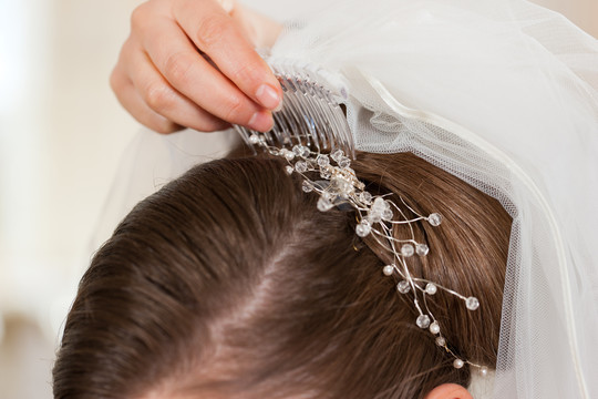 发型师在婚礼前给新娘扎上发型和新娘面纱，特写镜头