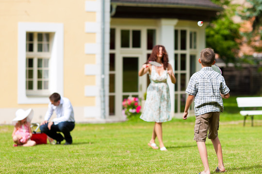 年轻幸福的家庭-在草地上玩耍的孩子和父母
