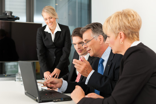 商务团队会议在办公室里用笔记本电脑，老板和他的员工，一个女人正看着摄像机