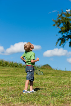 小男孩在夏天的户外打羽毛球