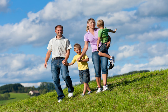 快乐的家庭（父亲、母亲和两个儿子）在美丽的夏日散步