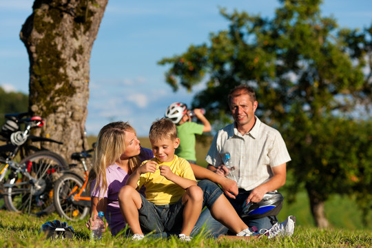 一个快乐的家庭（爸爸、妈妈和两个儿子）骑着自行车出游——他们有休息时间