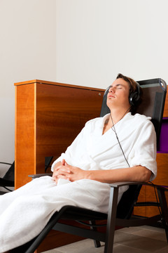 在安静的房间里，年轻人在水疗中心放松，戴着耳机听音乐