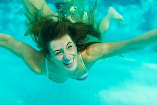 微笑的年轻女子在游泳池里游泳
