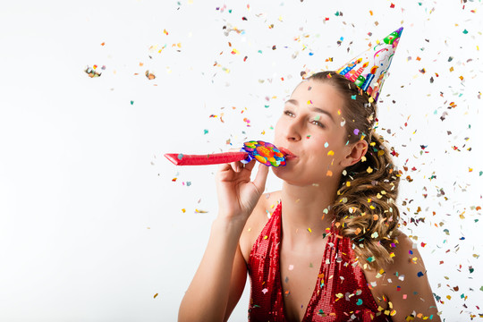 庆祝生日的女人在五彩纸屑旁用喇叭鸣叫