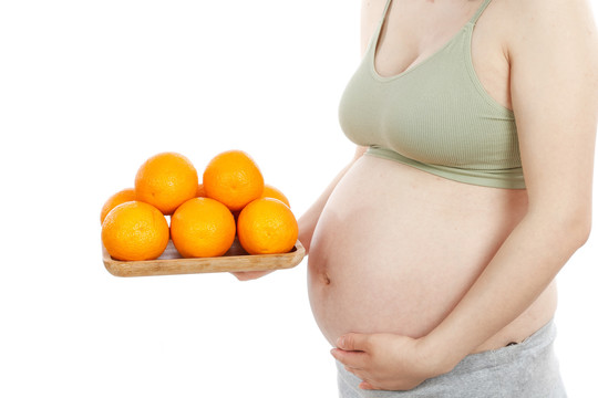 孕妇手上端着一盘新鲜橙子