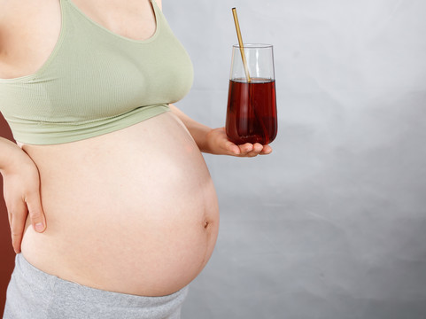 孕妇手上端着一杯葡萄汁