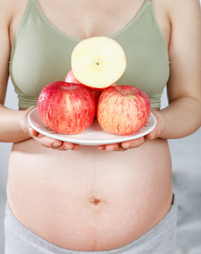 孕妇手上端着一盘红苹果