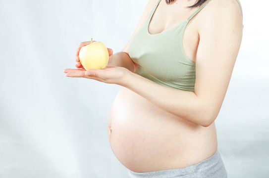孕妇手上拿着一个牛奶苹果