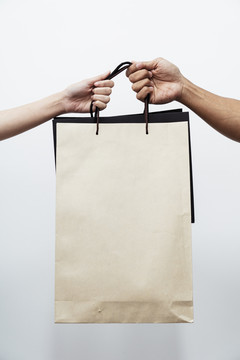 两个人手拿购物纸袋在白色背景上隔离在一起。