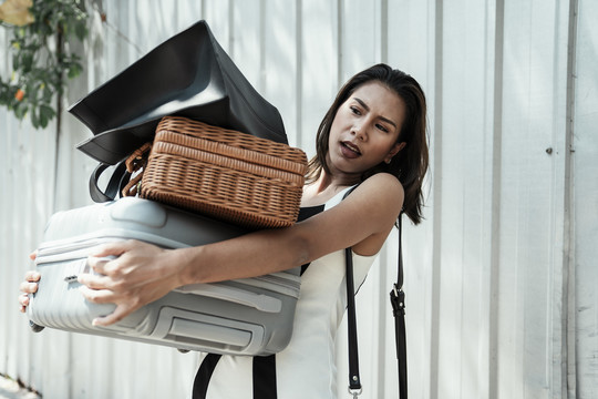 一位忙碌的亚泰妇女提着沉重的袋子和行李。坚强的女人。