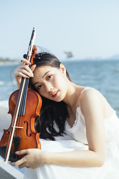 风大的日子里，黑发女人和她的小提琴在海上。