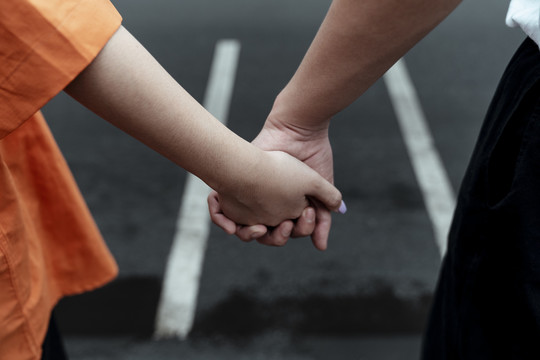 特写镜头中，一对夫妇在穿过马路时手牵着手。