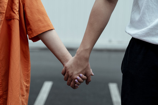 特写镜头中，一对夫妇在穿过马路时手牵着手。