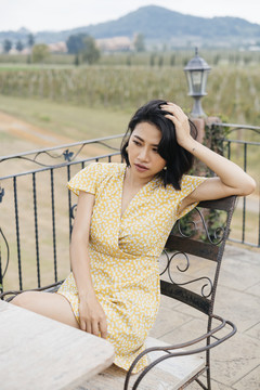 穿着黄色连衣裙的亚洲女人坐在椅子上摆着性感的姿势。