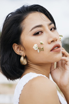 性感亚洲女孩的特写肖像，两颊上有一束小花。
